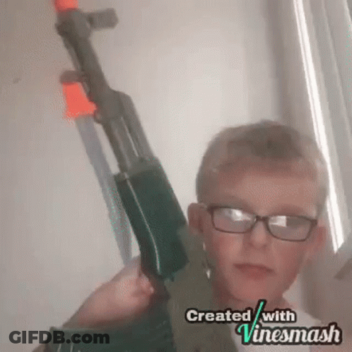 A Young Boy Wearing Glasses Is Holding A Toy Gun In His Hands . GIF