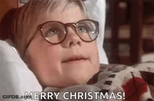A Young Boy Wearing Glasses Is Laying On A Bed And Saying Merry Christmas . GIF