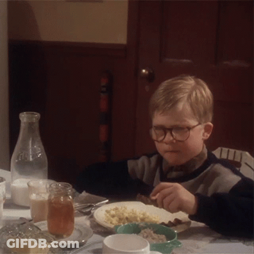 A Young Boy Wearing Glasses Is Sitting At A Table With A Plate Of Food GIF