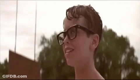 A Young Boy Wearing Glasses Is Smiling In Front Of A Field . GIF