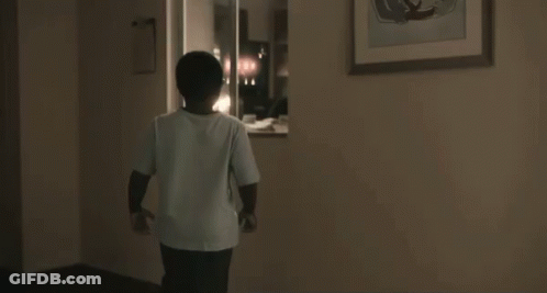 A Young Boy Wearing Glasses Is Standing In A Doorway With His Mouth Open And A Surprised Look On His Face . GIF