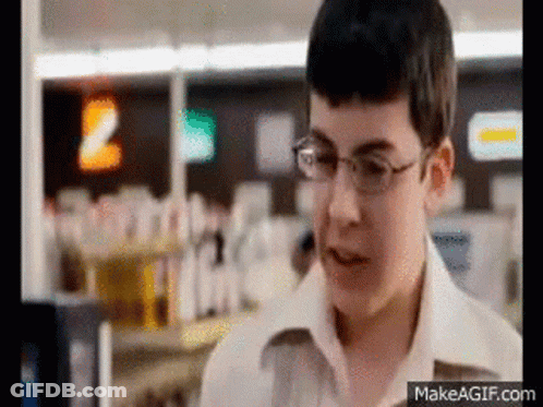 A Young Boy Wearing Glasses Is Standing In A Store Looking At Something . GIF