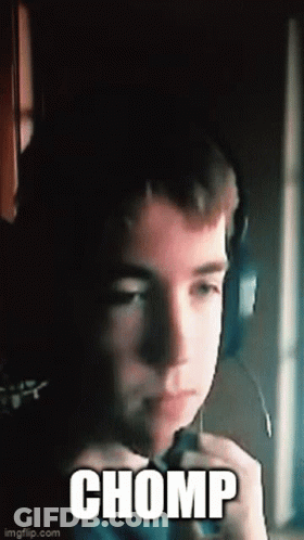 A Young Boy Wearing Headphones And A Microphone Is Making A Funny Face And Saying Chomp . GIF