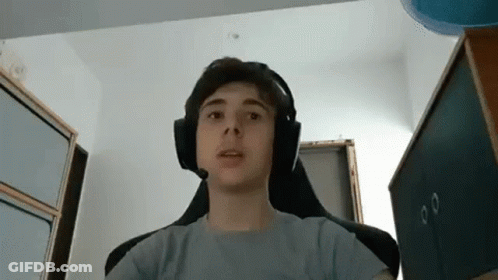 A Young Boy Wearing Headphones Is Sitting In A Chair In A Room . GIF