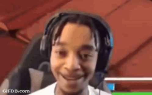 A Young Boy Wearing Headphones Is Smiling And Looking At The Camera . GIF