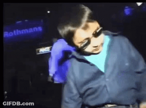 Boy In Blue Shirt Dancing In Front Of Rothmans Sign GIF