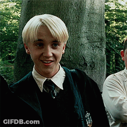 A Young Boy With Blonde Hair Is Wearing A Slytherin Uniform And Smiling GIF