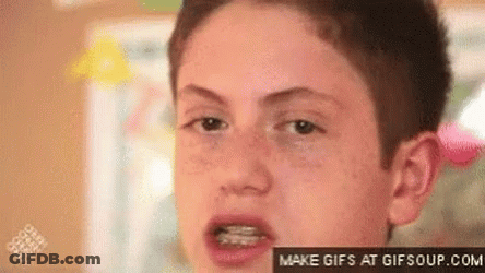 A Young Boy With Braces On His Teeth Is Looking At The Camera . GIF