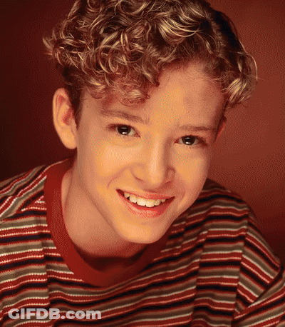 A Young Boy With Curly Hair Is Smiling For The Camera GIF