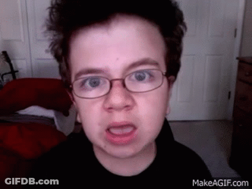 A Young Boy With Glasses Is Making A Funny Face . GIF
