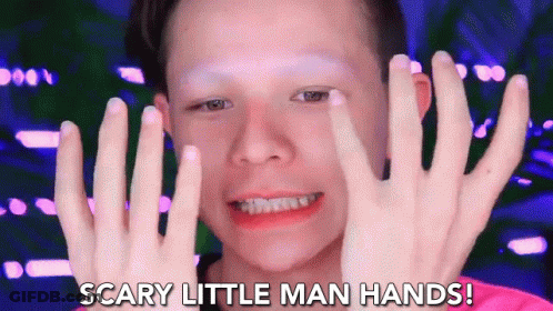 A Young Boy With Makeup On His Face Is Holding His Hands Up In Front Of His Face And Saying Scary Little Man Hands . GIF
