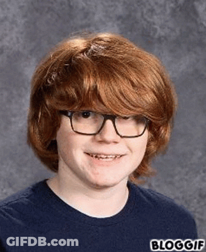 A Young Boy With Red Hair And Glasses Is Smiling For A Picture . GIF