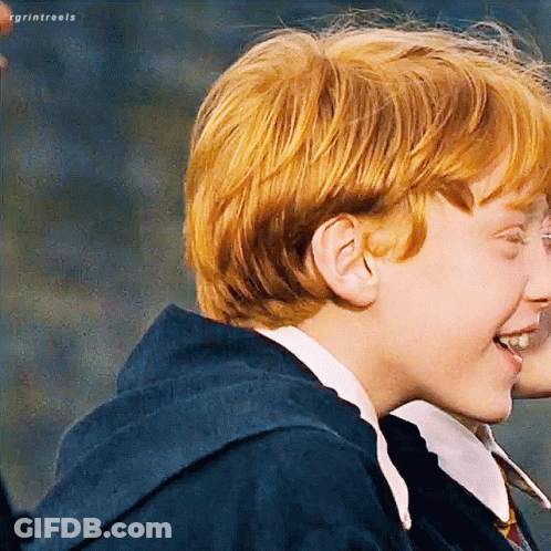 A Young Boy With Red Hair Is Smiling While Wearing A Blue Hoodie . GIF