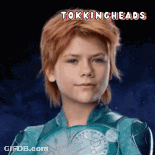 A Young Boy With Red Hair Is Wearing A Blue Suit With The Words Tokingheads Written Above Him GIF