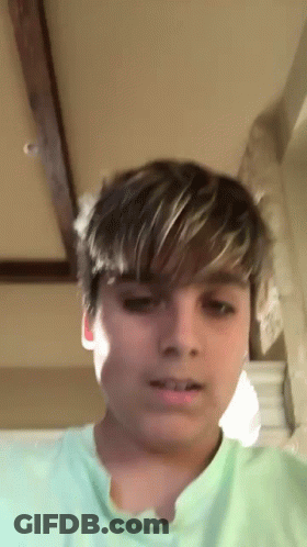A Young Boy With Short Hair Is Wearing A Green Shirt . GIF