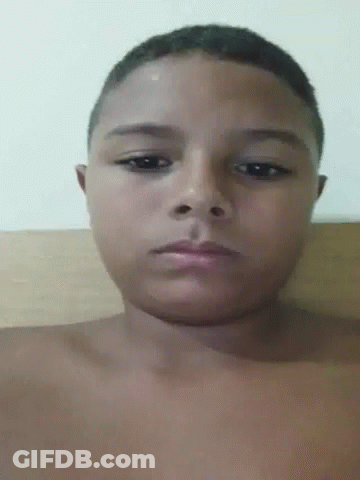 A Young Boy Without A Shirt Is Looking At The Camera With A Serious Look On His Face . GIF