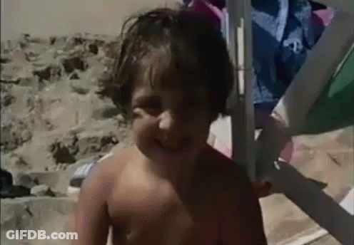 A Young Boy Without A Shirt Is Standing On The Beach GIF