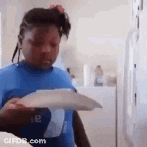 A Young Girl In A Blue Shirt Is Holding A Piece Of Paper In Her Hand . GIF