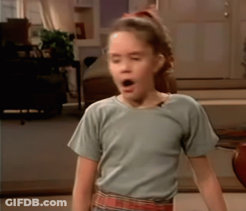 A Young Girl In A Blue Shirt Is Making A Funny Face GIF