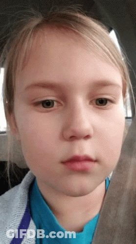 A Young Girl In A Blue Shirt Looks At The Camera With A Serious Look On Her Face GIF
