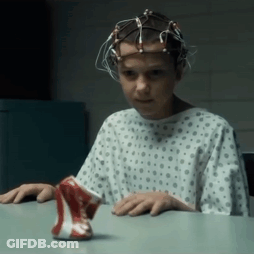 A Young Girl In A Hospital Gown Is Sitting At A Table With A Can Of Soda In Front Of Her GIF