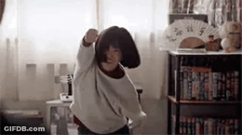 A Young Girl Is Dancing In A Room With A Fan . GIF