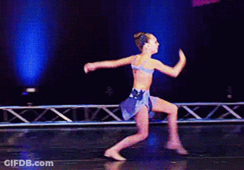 A Young Girl Is Dancing On A Stage In A Blue Dress GIF