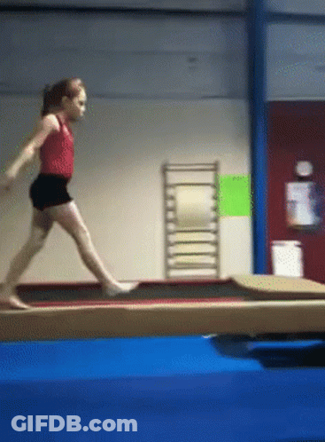 A Young Girl Is Doing A Trick On A Balance Beam In A Gym GIF