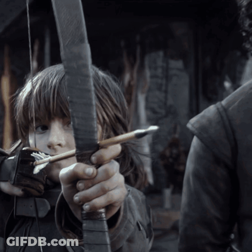 A Young Girl Is Holding A Bow And Arrow In Her Hands GIF