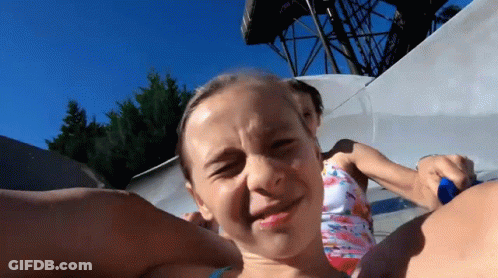 A Young Girl Is Making A Funny Face While Riding A Water Slide GIF