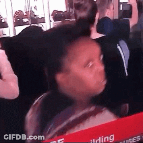 A Young Girl Is Making A Funny Face While Sitting In A Crowd Of People . GIF