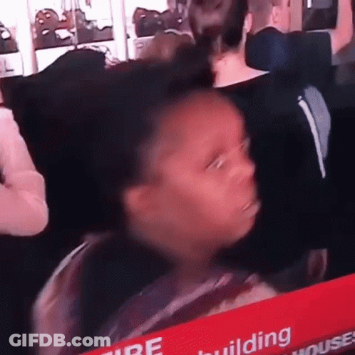 A Young Girl Is Sitting In A Crowd Of People Looking At A Tv Screen . GIF