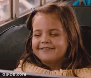 A Young Girl Is Smiling While Sitting On A Bus . GIF