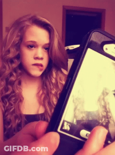 A Young Girl Is Taking A Picture Of Herself On Her Phone GIF