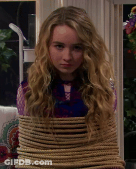 A Young Girl Is Tied Up With A Rope And Looking At The Camera GIF