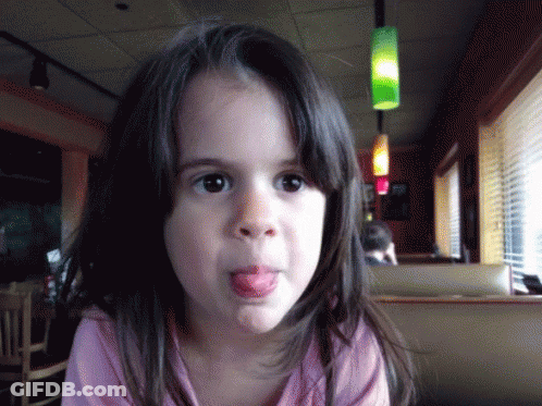 A Young Girl Sticking Her Tongue Out In A Restaurant GIF
