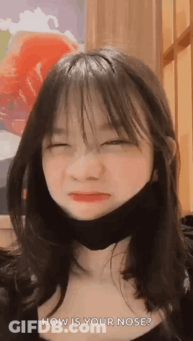 A Young Girl Wearing A Black Mask Is Making A Funny Face . GIF