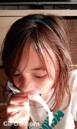 A Young Girl Wearing A Shirt That Says ' Hawaii ' On It Is Chewing On A Piece Of Paper GIF