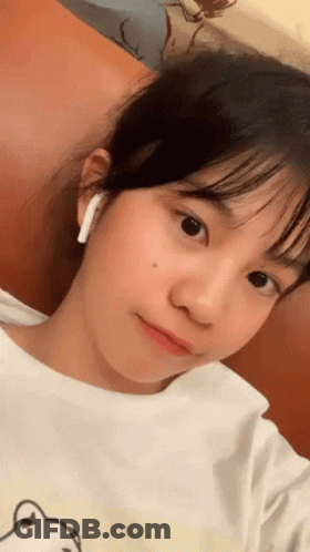 A Young Girl Wearing A White Shirt And Ear Buds GIF