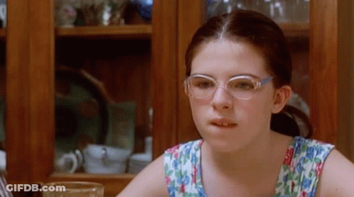 A Young Girl Wearing Glasses Is Sitting At A Table With A Glass Of Water GIF