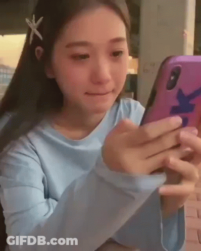 A Young Girl With A Starfish In Her Hair Is Looking At Her Cell Phone . GIF