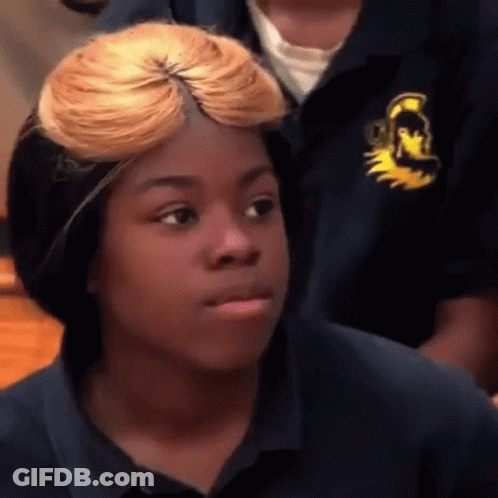 A Young Girl With Blonde Hair Is Making A Funny Face While Wearing A Blue Shirt . GIF