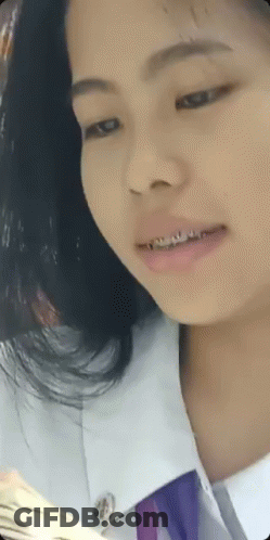 A Young Girl With Braces On Her Teeth Is Wearing A White Shirt And Purple Tie GIF