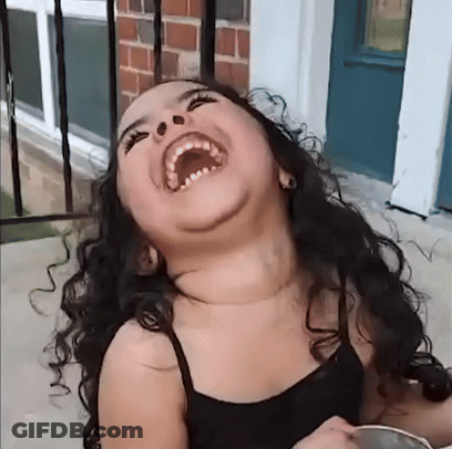 A Young Girl With Curly Hair Is Laughing With Her Mouth Wide Open GIF