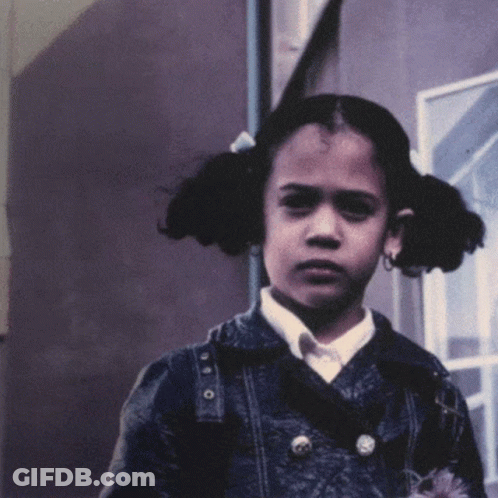 A Young Girl With Pigtails Is Wearing A Denim Jacket And A White Shirt GIF