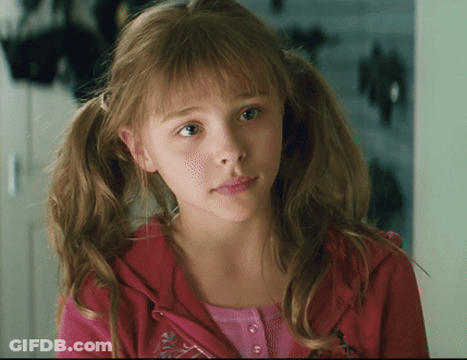 A Young Girl With Pigtails Is Wearing A Pink Shirt And A Red Jacket GIF