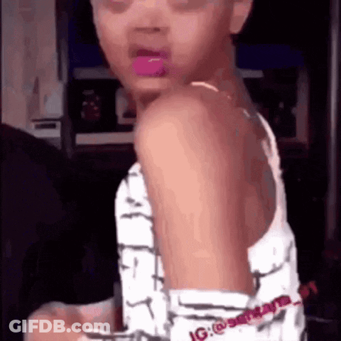 A Young Girl With Pink Lipstick On Her Lips Is Standing In A Room . GIF
