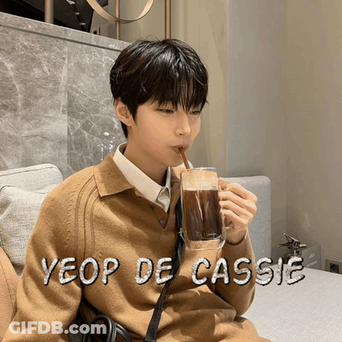 A Young Man Drinking A Cup Of Coffee With The Name Yeop De Cassie Written On The Bottom GIF