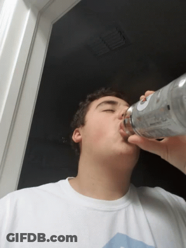 A Young Man Drinking From A Bottle With A Label That Says Vodka GIF