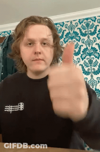 A Young Man Giving A Thumbs Up In Front Of A Wallpaper GIF